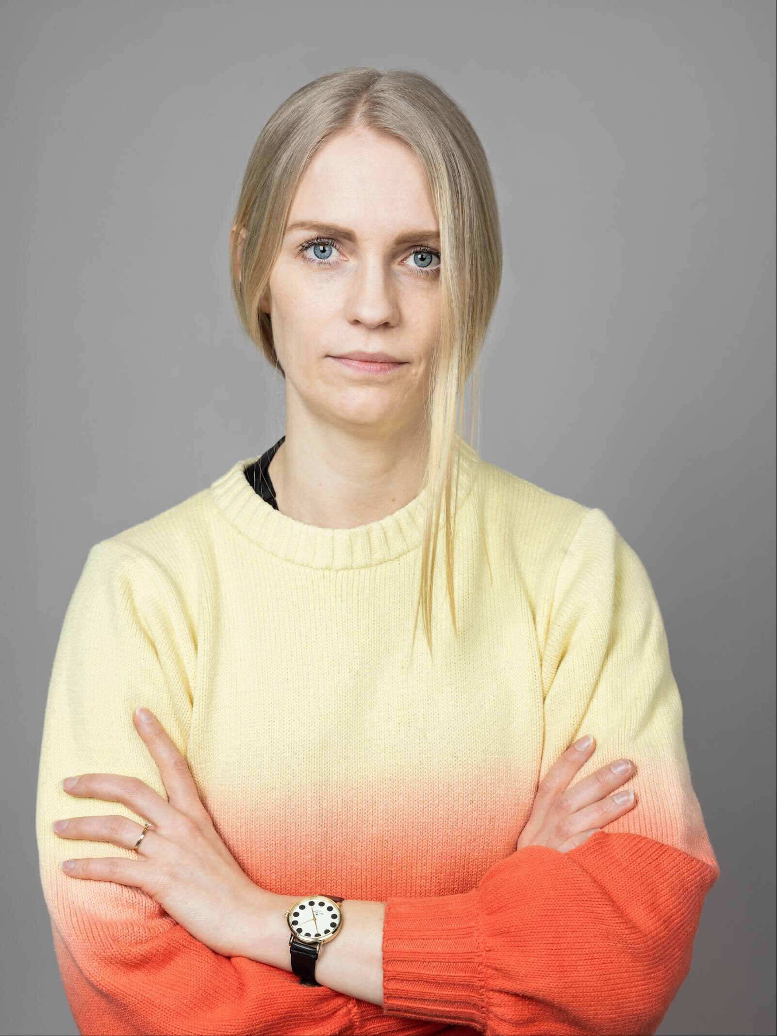 A woman with a yellow and orange sweater crossing her arms