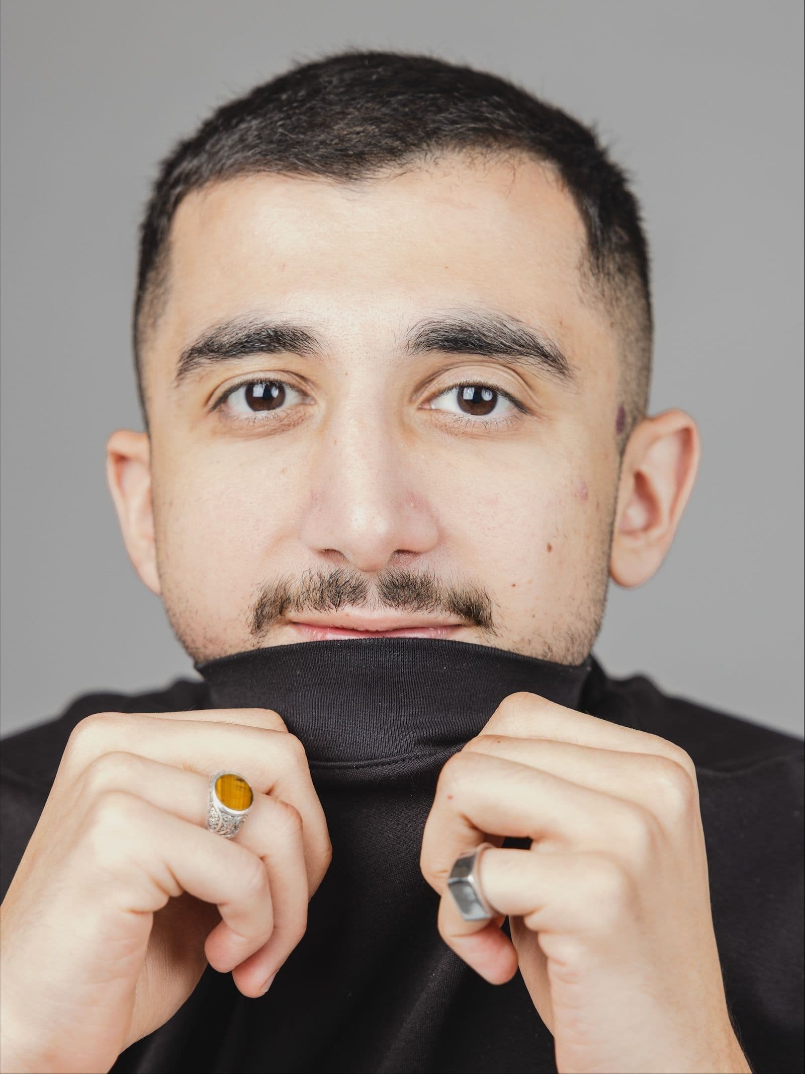 A man with covering his chin with the neck of his black t-shirt