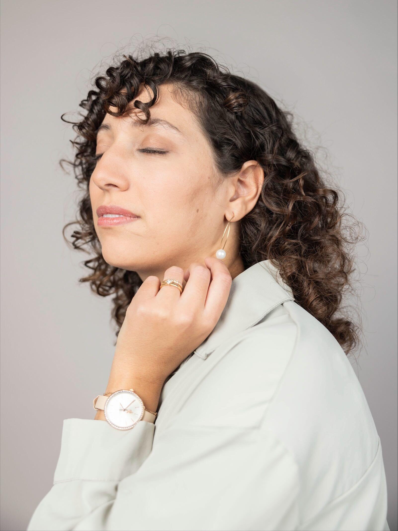 A woman with closed eyes holding up her hand to her face